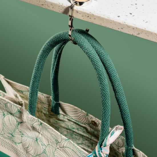 AURA Bag Hanger unfolded, holding tote bag handles from a countertop edge