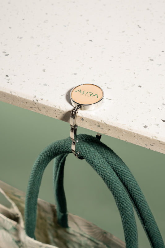 AURA Bag Hanger hook in use, holding bag handles from a table edge