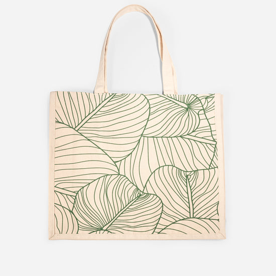 The AURA Canvas Tote in natural canvas with green palm leaf line-art print, front view