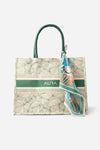 Front view of AURA Signature Tote Bag with green leaf print, green woven handles and AURA logo stripe