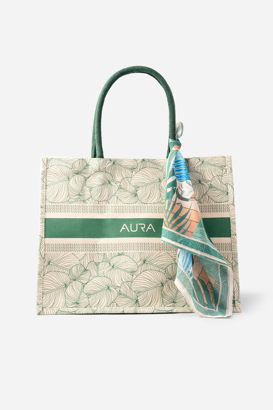 Front view of AURA Signature Tote Bag with green leaf print, green woven handles and AURA logo stripe