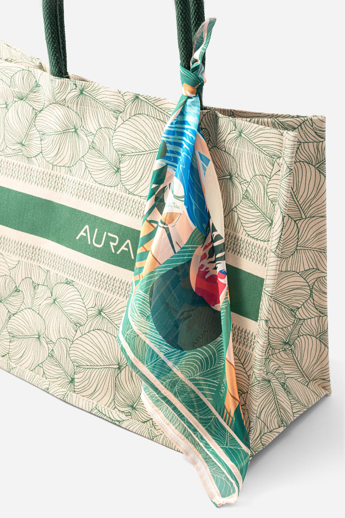 Close-up of AURA Signature Tote Bag corner with green padded handle and scarf styling detail