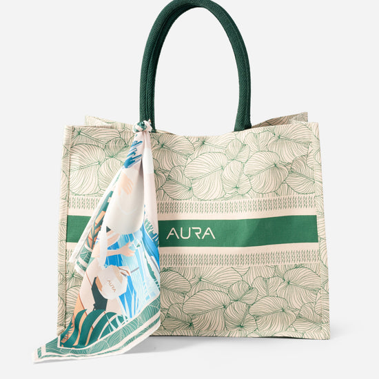 Angled front view of AURA Signature Tote Bag showing green leaf print and AURA logo band