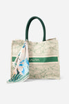 Angled front view of AURA Signature Tote Bag showing green leaf print and AURA logo band