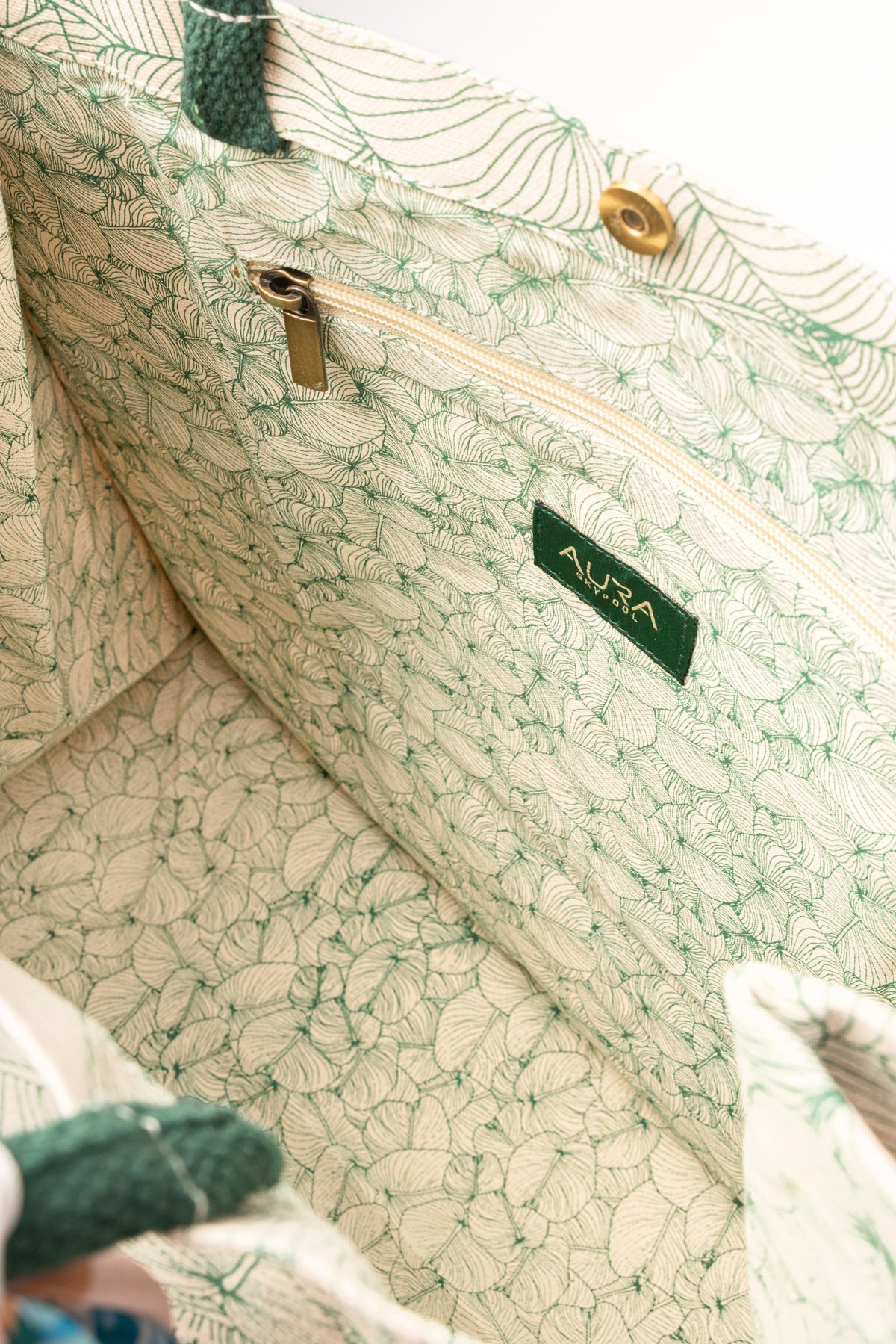 Open interior of AURA Signature Tote Bag with matching leaf-print lining and zip pocket