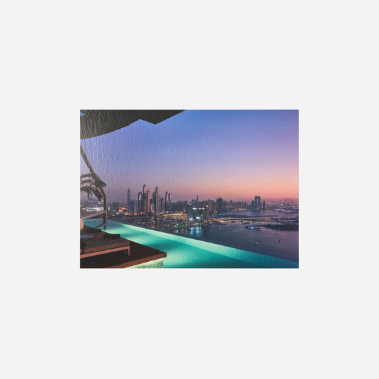 AURA Skypool postcard, pool edge glowing teal at sunset over the skyline