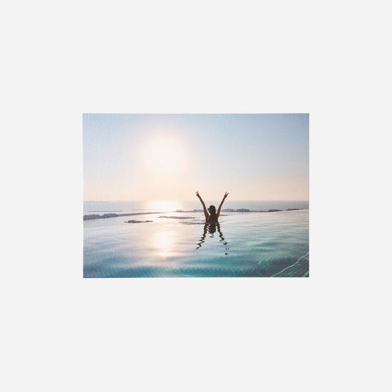 AURA Skypool postcard, silhouette in the pool with arms raised at sunrise