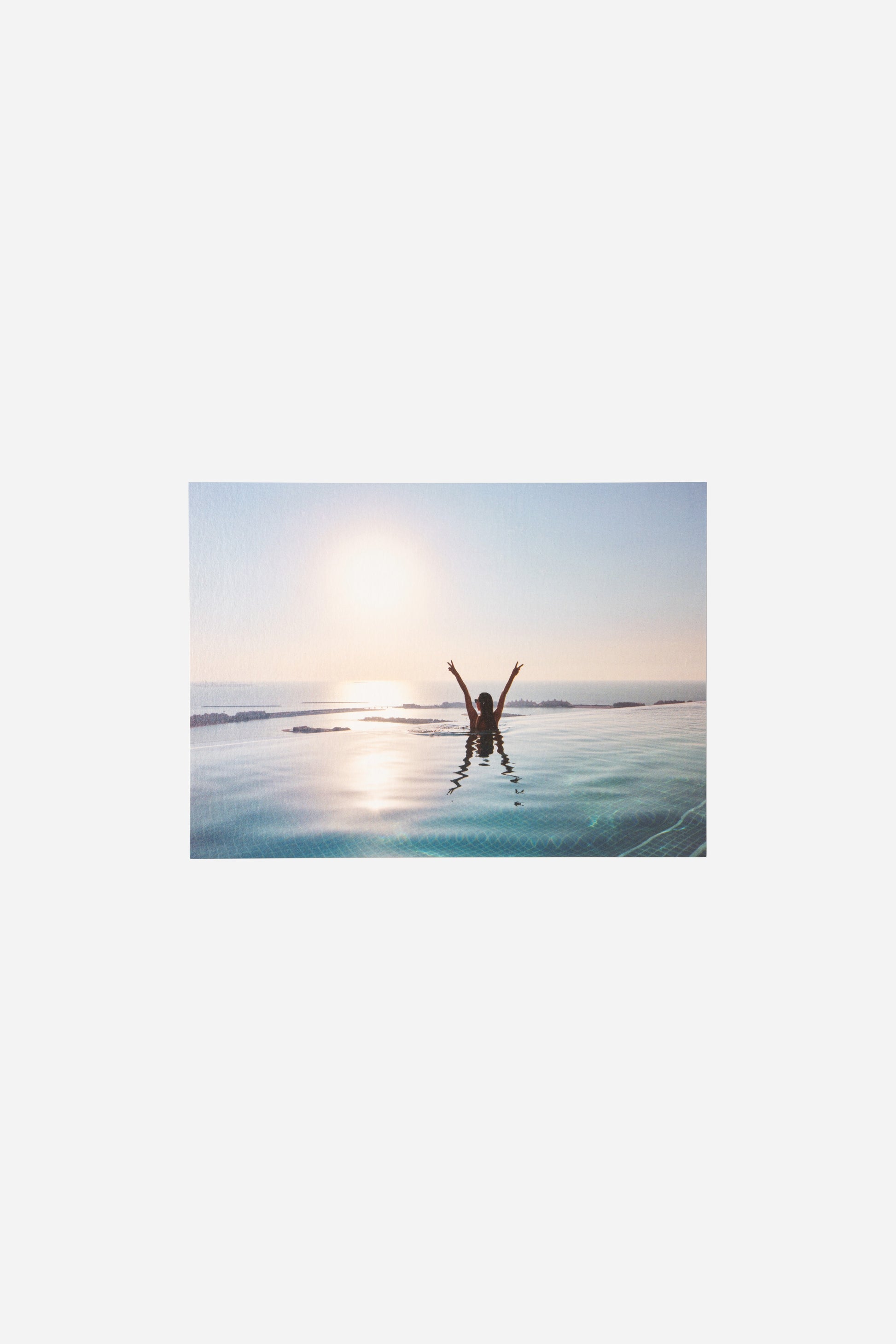 AURA Skypool postcard, silhouette in the pool with arms raised at sunrise