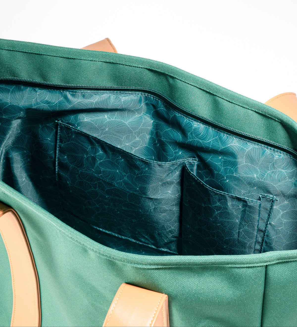 Open interior of AURA Beach Bag Palm Green showing teal leaf-print lining and slip pockets