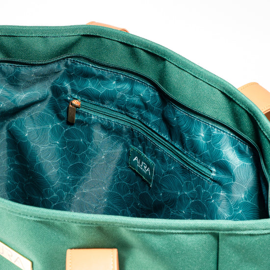 Interior zip pocket detail of AURA Beach Bag Palm Green with teal leaf-print lining