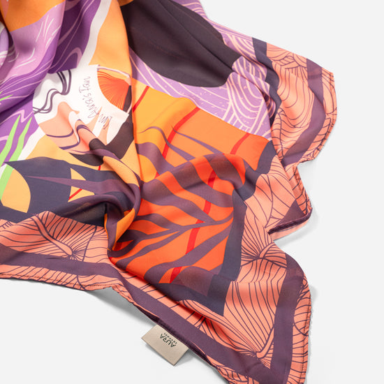 Dubai Skyline Sarong in coral, draped close-up showing silk print and AURA label