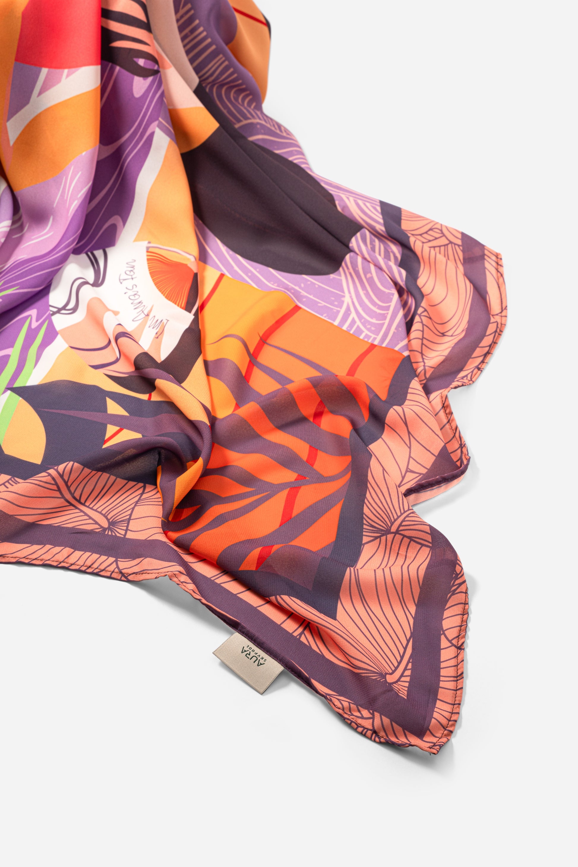 Dubai Skyline Sarong in coral, draped close-up showing silk print and AURA label