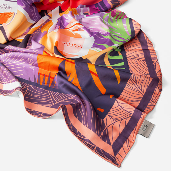 Dubai Skyline Silk Scarf in Coral, draped close-up showing the AURA woven label