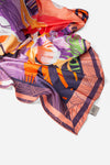 Dubai Skyline Silk Scarf in Coral, draped close-up showing the AURA woven label