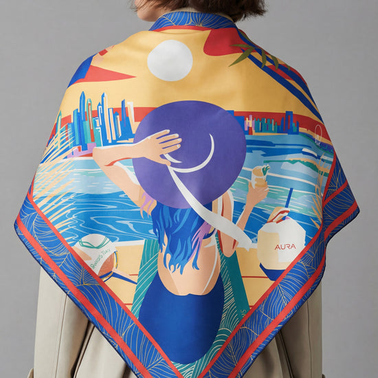 AURA Dubai Skyline Silk Scarf in Indigo, worn draped over the shoulders with a trench coat