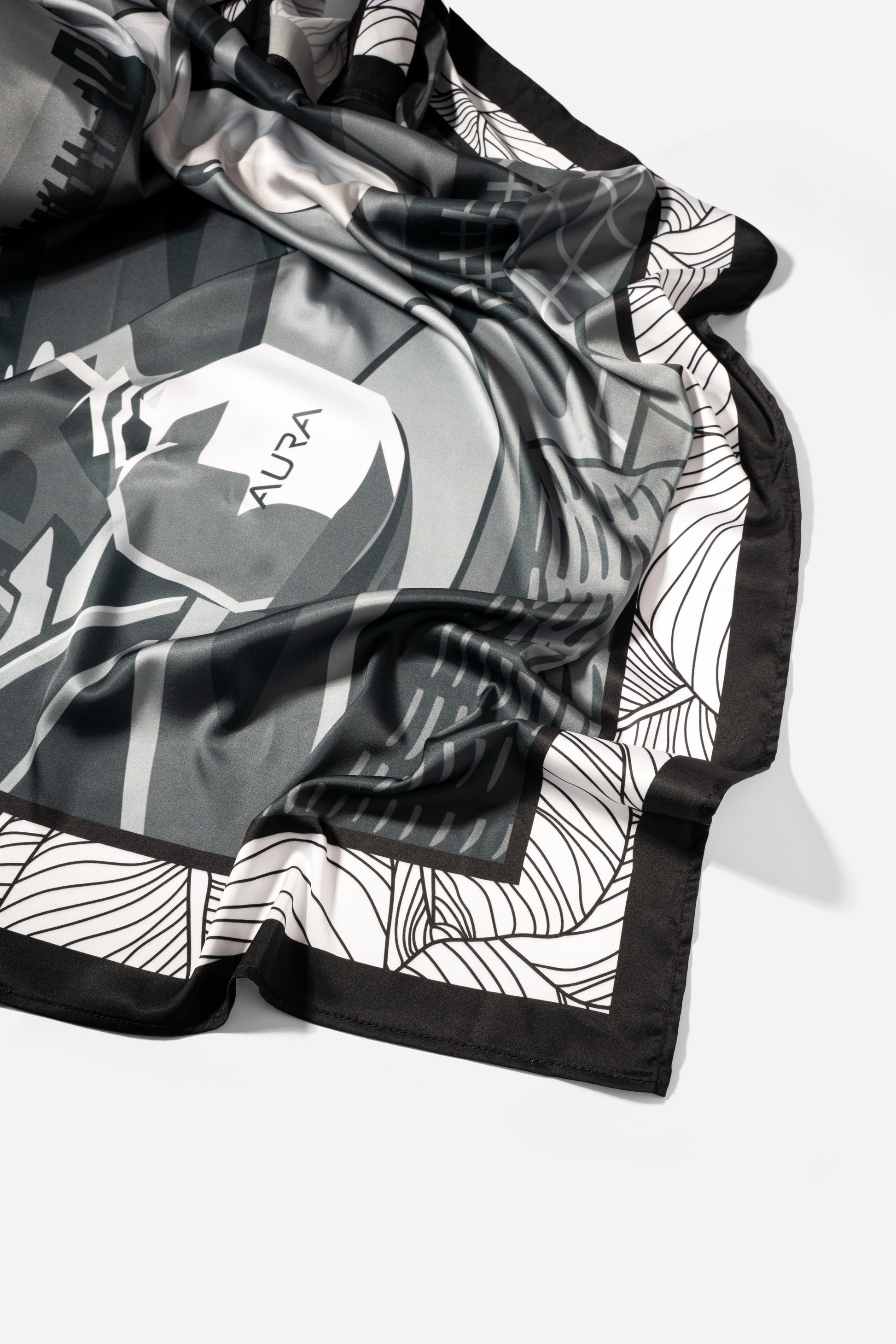 Monochrome Skyline Silk Scarf, draped close-up showing the AURA label and border print