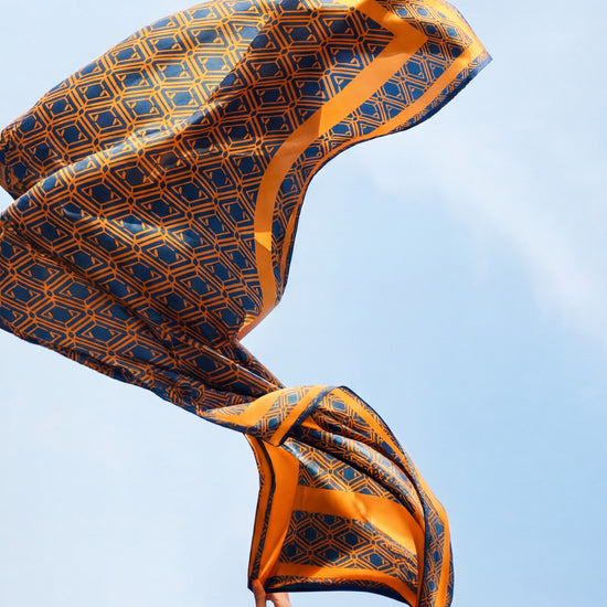 Monogram Sarong in Midnight Mirage, held up and caught in the wind against a blue sky