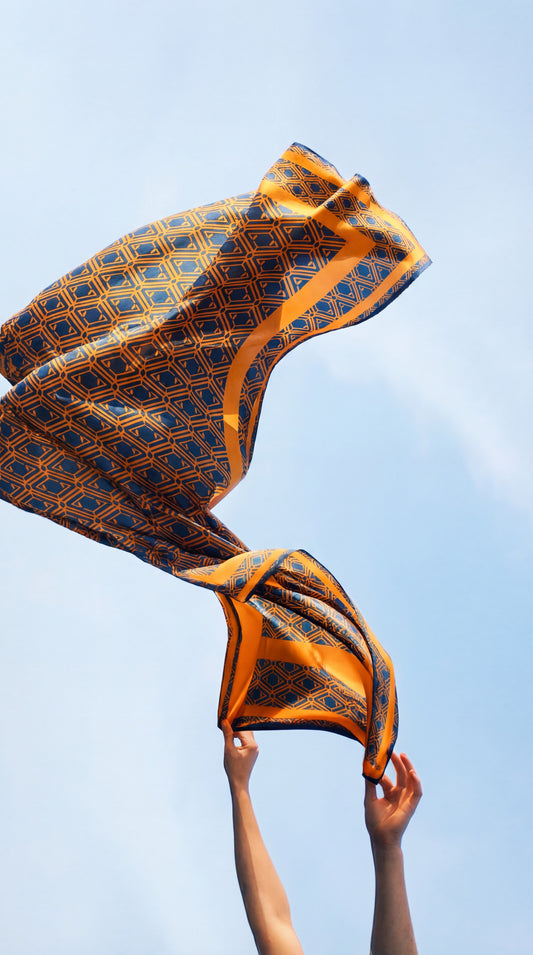 Monogram Sarong in Midnight Mirage, held up and caught in the wind against a blue sky