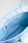 Open interior of The Monogram Bag Azure Blue showing sky-blue satin lining and zip pocket
