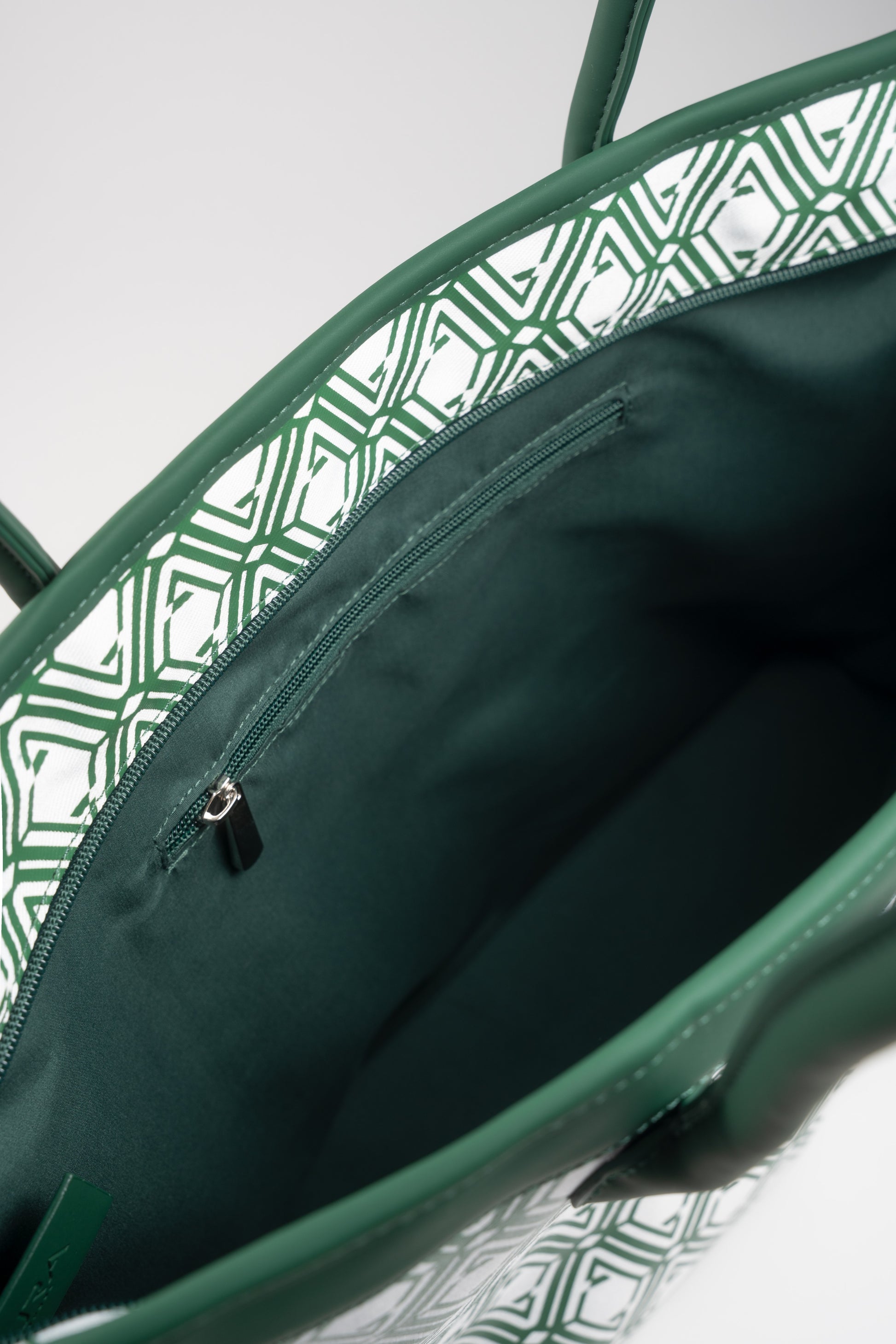 Open interior of The Monogram Bag Evergreen showing dark green satin lining and zip pocket