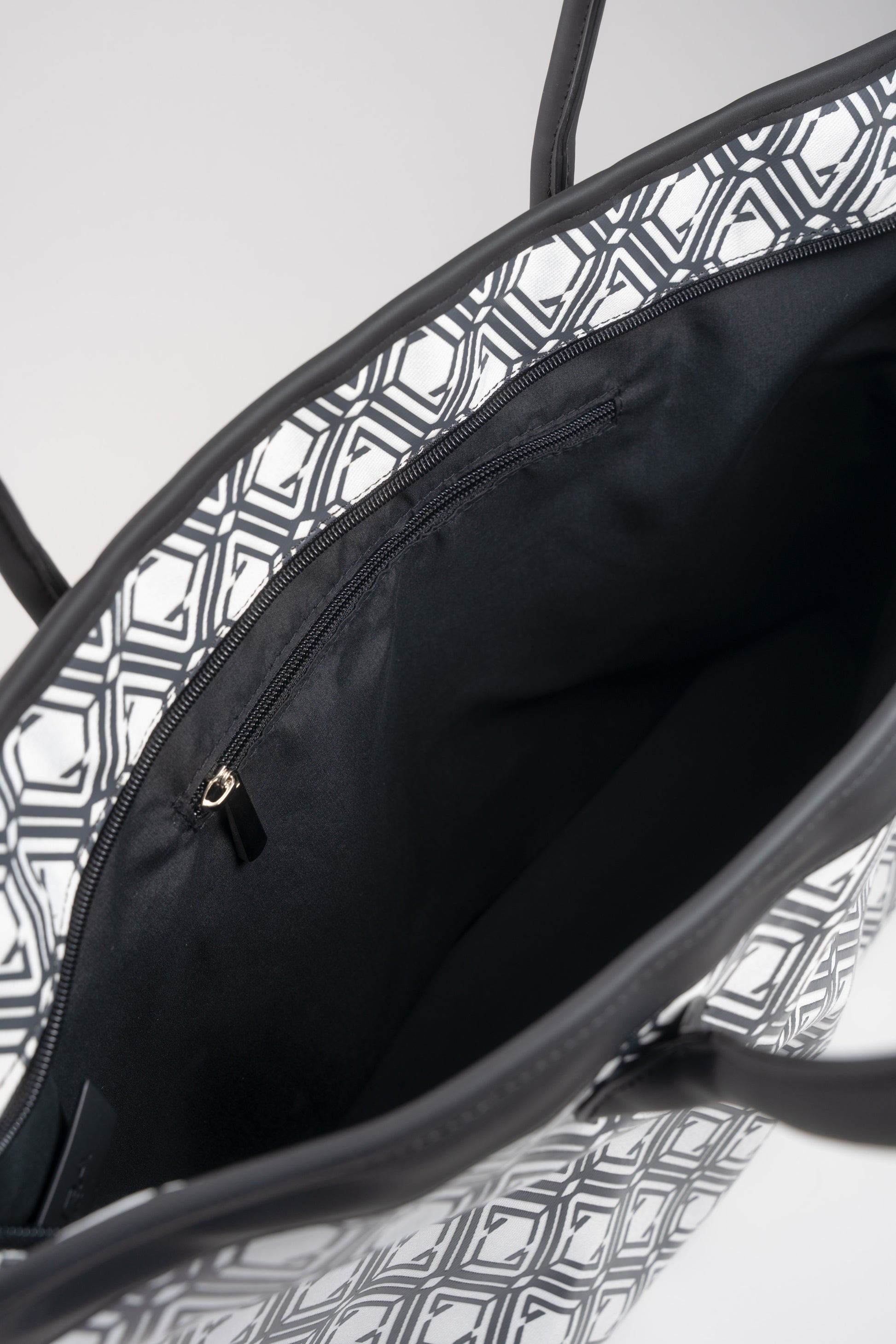 Open interior of The Monogram Bag Night Black showing black satin lining and gold-tone zip pocket