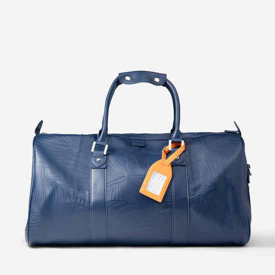 AURA Weekender Duffle in horizon blue with leaf-embossed leather and orange luggage tag