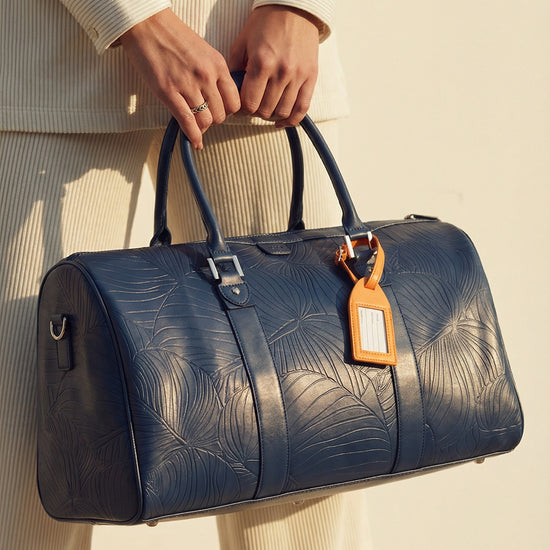 Model carrying AURA Weekender Duffle in horizon blue leaf-embossed leather