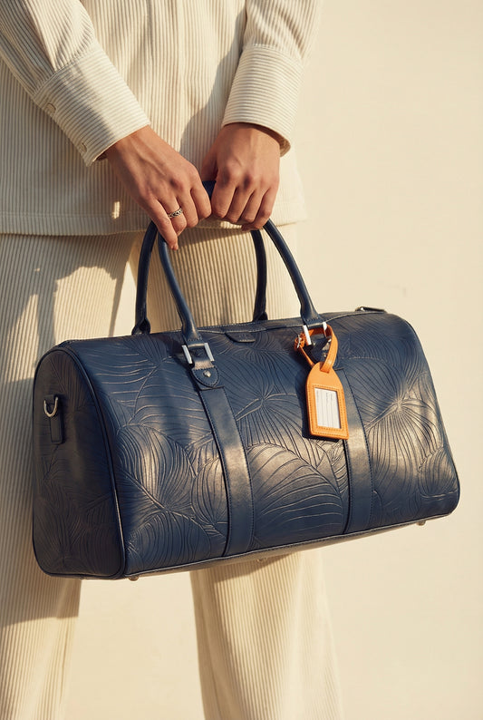 Model carrying AURA Weekender Duffle in horizon blue leaf-embossed leather