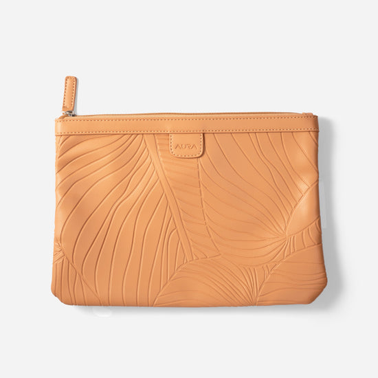 Travel Pouch in Clay, flat lay showing leaf-embossed leather and zip pull