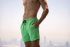 Voyager Swim Shorts in lime green, worn against the Dubai skyline