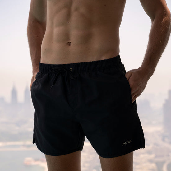 Voyager Swim Shorts in night black, worn against the Dubai skyline