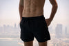 Voyager Swim Shorts in night black, worn against the Dubai skyline