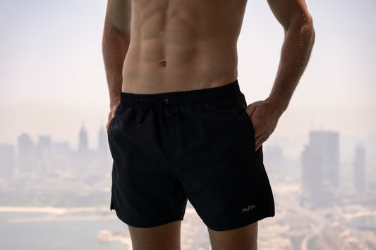 Voyager Swim Shorts in night black, worn against the Dubai skyline